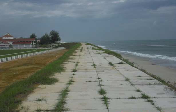 Concrete revetment walkway running along a sandy beach